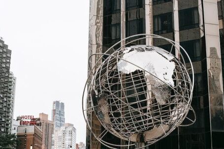 Property Empire - Contemporary stainless steel unisphere sculpture located near modern skyscrapers against Trump tower on street in New York city on Manhattan