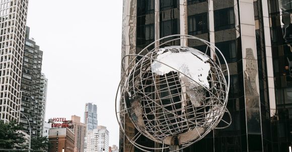 Property Empire - Contemporary stainless steel unisphere sculpture located near modern skyscrapers against Trump tower on street in New York city on Manhattan