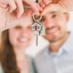 Property Investing - Happy Couple Holding and Showing a House Key