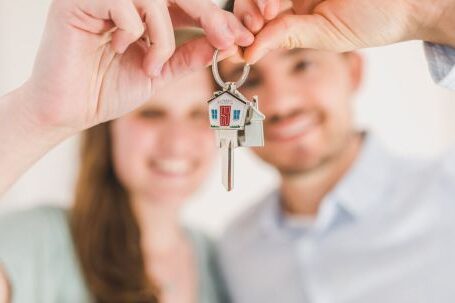 Property Investing - Happy Couple Holding and Showing a House Key